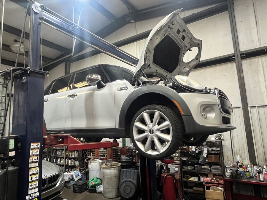 Mini Cooper with the hood open on a lift at Athens Import Auto Repair